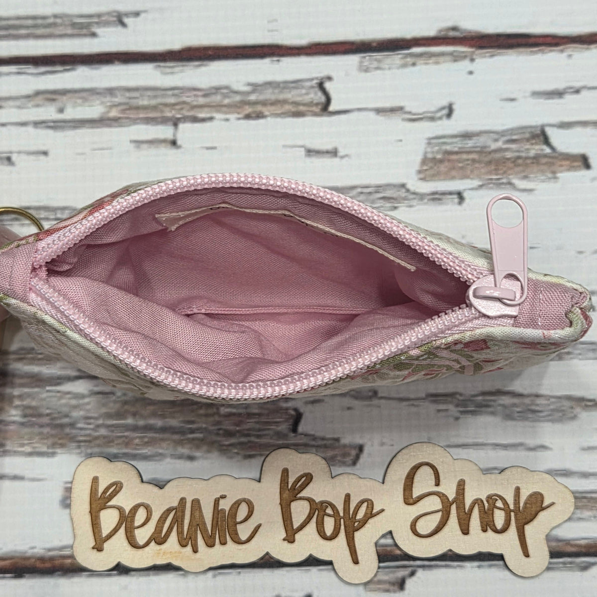 Pink zipper pouch with wooden nameplate on a rustic wooden background